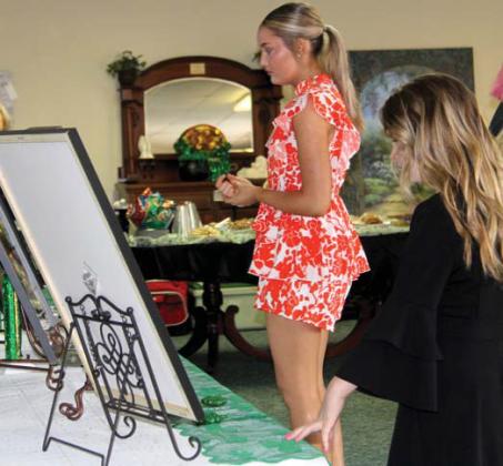 Miss Dublin contestant Nicole Foster and Junior Miss Dublin contestant Charlotte Meador look at photos from past pageants at the interview and reception Sunday, March 3 at First Methodist Church. Wyndi Veigel-Gaudette | Citizen staff photo