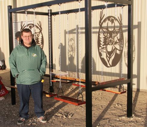 Zander Bullard posed with a red cedar table with swing seats constructed by Dublin FFA students and shown by him at the 2023 Erath County Jr. Livestock Show. Bullard was presented with Reserve Champion in the Ag Mechanics Show and first in Home and Yard Convenience.