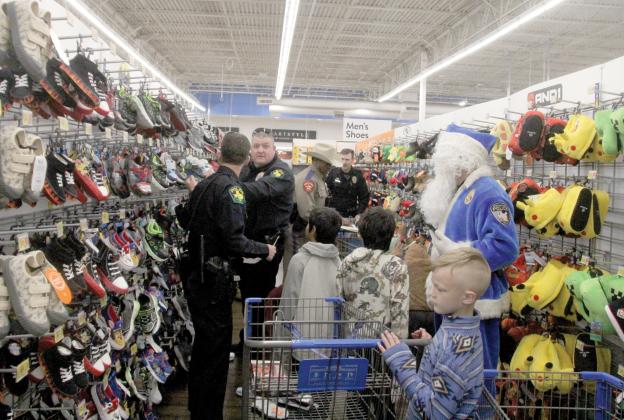 Dublin Police Chief Cameron Ray helps other law enforcement officers choose shoes for kids they are helping shop with at the 5th annual Erath County Shop with a Cop, Dec. 19, 2024. The annual event provides Erath County kids $250 to shop with at the Stephenville Walmart and they are paired with area law enforcement personnel.