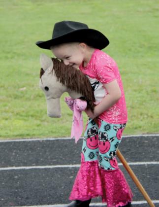 A student hugs her stick horse.
