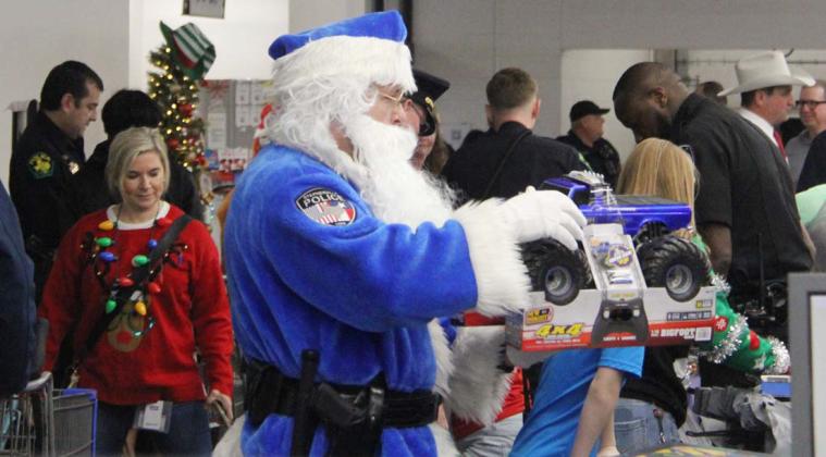 Santa in Blue holds up a Monster Truck to help check out an eager child in Erath County’s Shop with a Cop event. Wyndi Veigel-Gaudette| Citizen staff photo