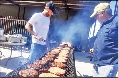 Dublin Rotary Club members Lee Leatherwood and Pat Leatherwood show burger flipping expertise at the grill behind the Station at First National Bank Thursday. Rotary Club members, who often fire up the grill for community, events lent a hand, or several, to prepare 700 burgers in preparation for the Stephenville football game hosted at Dublin’s Cervetto Field Friday night. Paul Gaudette | Citizen staff photo