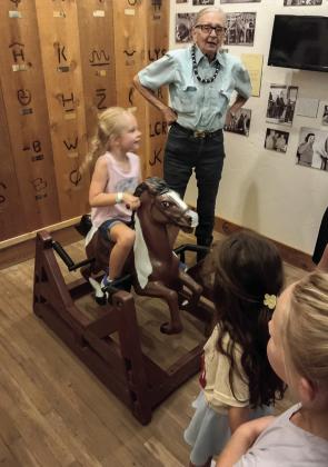 Dublin Rodeo Heritage Museum Board Member Sharron Dean helps kids enjoy some ‘bronc ridin’ inside the museum during a tour. Submitted photo
