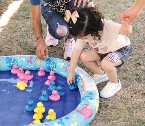 Top right, Hispanic Heritage Festival Co-organizer and Chamber Director Sandra Espinoza shows off a specially labeled Dublin Bottling Works soda for the event. Above, kids enjoy hunting for ducks at a vendor booth. Wyndi Veigel | Citizen staff photos