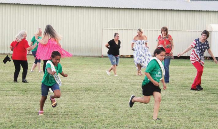 Little Miss Dublin contestants play on the grass during the Dublin Area Reunion Street Dance held Saturday night at Dublin Bottling Works’ Celebration Park while line dancers move to country music. Wyndi Veigel | Citizen staff photo