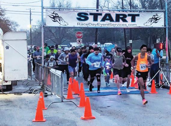 Runners emerge from the Shamrock Shuffle starting line on North Park by the Dublin Public Library Saturday, March 16 just as day begins to break. Paul Gaudette | Citizen staff photo