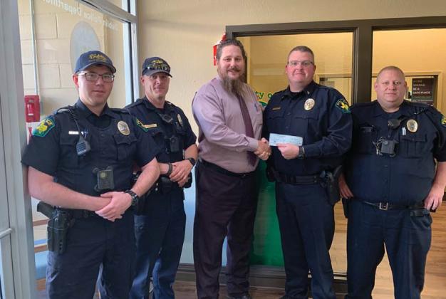 Dublin Police Chief Cameron Ray and members of the police department accept a donation from Heath Allen for Shop with a Cop. Submitted photo
