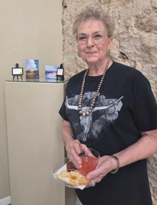 Artist Pat Sharp enjoys refreshments beside her tiny acrylic paintings of clouds and landscapes. Wyndi Veigel-Gaudette | Citizen staff photo