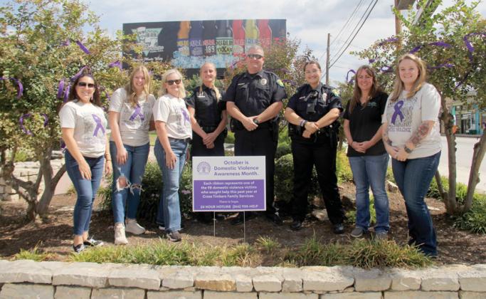 Employees with Cross Timbers Family Services and the Dublin Police Department combined forces on Monday to tie 98 ribbons around trees at the Corner Lot in observance of National Domestic Violence Awareness Month in October. Wyndi Veigel | Citizen staff photo