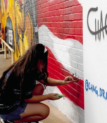Incoming Dublin High School Freshman Selene Moreno signs her signature to a new mural in downtown Stephenville across from the Stephenville Police Department. Selene was the winner of a regional 9-1-1 art contest. Wyndi Veigel-Gaudette | Citizen staff photo