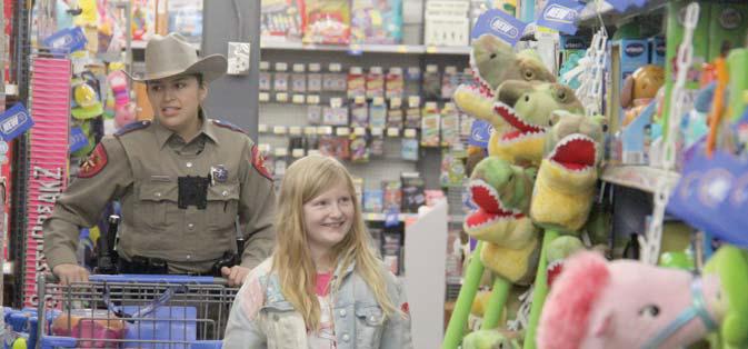 A State Trooper aids a young girl in shopping for Christmas presents. Paul Gaudette | Citizen staff photo