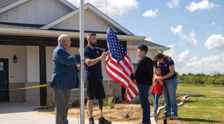 U.S. Army Specialist Kyle Beddow hangs up an American flag in front of his new home located in Stephenville. SPC Beddow was gifted a home through Homes For Our Troops, a nonprofit that builds homes for injured veterans. Courtesy photo