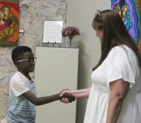 Above, a young man learns how to properly shake hands with KeliJon Nance at Manners Camp hosted by Cross Timbers Fine Arts Council. Below, young ladies learn about proper meal etiquette. Paul Gaudette and Wyndi Veigel | Citizen staff photo