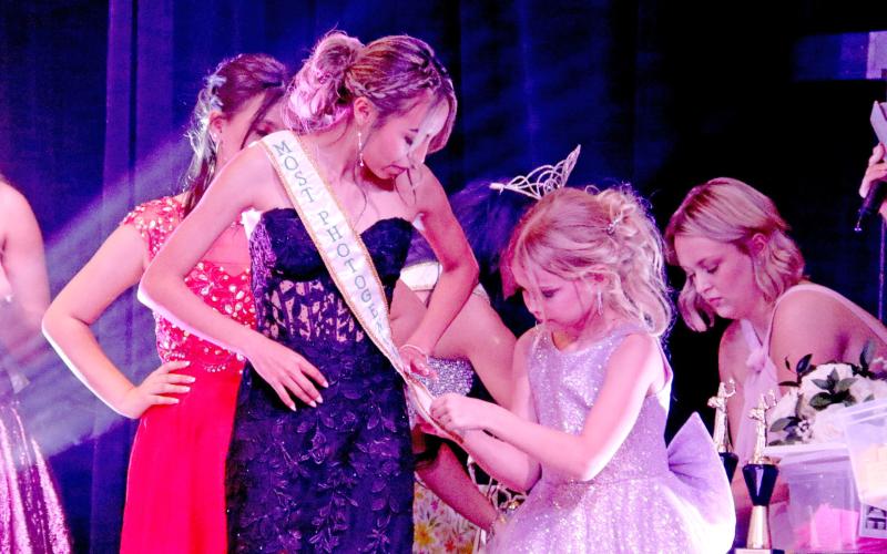 Junior Miss Dublin contestant Gentry Baugh shows off her kindness as she help pins the recently received sash of Miss Most Photogenic Jocelyn Perez. Wyndi Veigel-Gaudette | Citizen staff photo