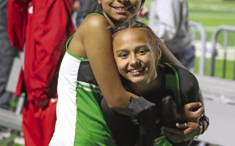 Dublin Lions Diana Macias and McKayla Hernandez huddle together during a ‘warm-up’ for the Girls 1600 meter run at a chilly Dublin Invitational Track Meet. Paul Gaudette | Citizen staff photo