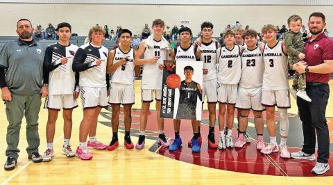 Lingleville Cardinals coaches and players join senior Issac Martinez (center, with poster) in congratulations as he eclipsed 1500 career points during the Feb. 10 preview playoff game against Ballinger at home. Paul Gaudette | Citizen staff photo