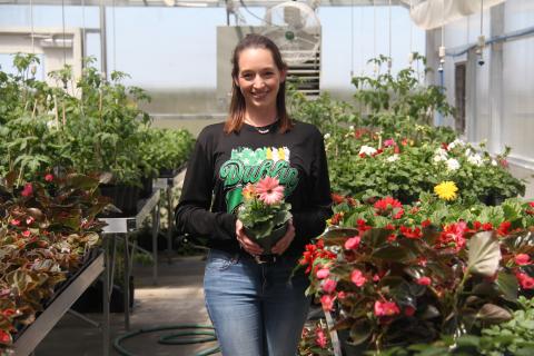 Plant photo with ag sponsor Sophie Hayhurst. She is holding a gerber daisy plant.