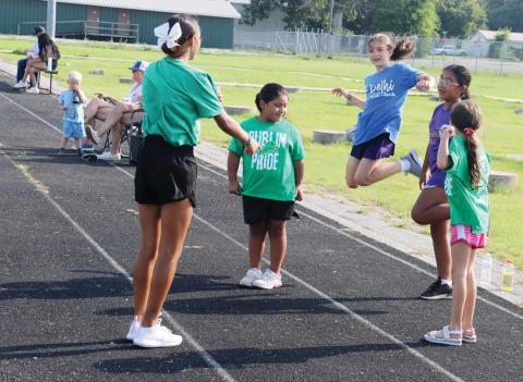 Dublin High School cheerleader McKayla Hernandez (above) leads cheer students through proper leaps at the Dublin Youth Football League summer camp July 14-16 at the memorial stadium. Below, players run through passing and receiving drills on the field. Paul Gaudette | Citizen staff photo