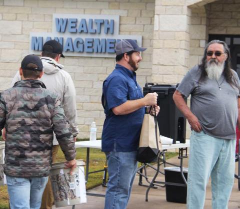 Ira Goodman, the General Manager at Mattressville Stephenville, makes announcements to the line while volunteers help organze the turkeys for the giveaway. Paul Gaudette | Citizen staff photo