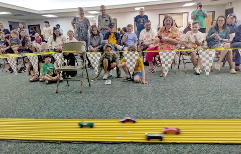 Audience members watch in fascination as cars zoom by at the annual Pinewood Derby held Saturday, March 21 at First Methodist Church. Paul Gaudette | Citizen staff photo