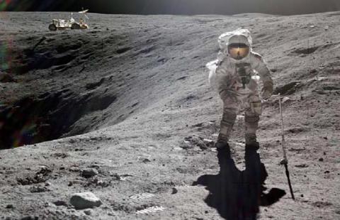 Astronaut Charlie Duke, lunar module pilot, is photographed by astronaut John W. Young, commander, collecting lunar samples during the first Apollo 16 extravehicular activity (EVA) at the Descartes landing site. Duke is standing at the rim of Plum Crater. The parked Lunar Roving Vehicle (LRV) can be seen in the left background. | NASA