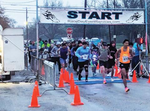 Runners emerge from the Shamrock Shuffle starting line on North Park by the Dublin Public Library Saturday, March 16 just as day begins to break. Paul Gaudette | Citizen staff photo