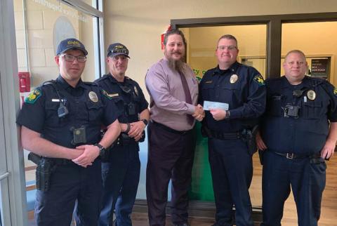 Dublin Police Chief Cameron Ray and members of the police department accept a donation from Heath Allen for Shop with a Cop. Submitted photo