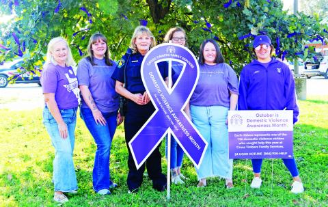 Employees and volunteers from Cross Timbers Family Services along with Dublin Police Detective Nanci Wilson tie purple ribbons in honor of Domestic Abuse Awareness Month on a tree near the Dublin Annex. Wyndi Veigel-Gaudette | Citizen staff photo